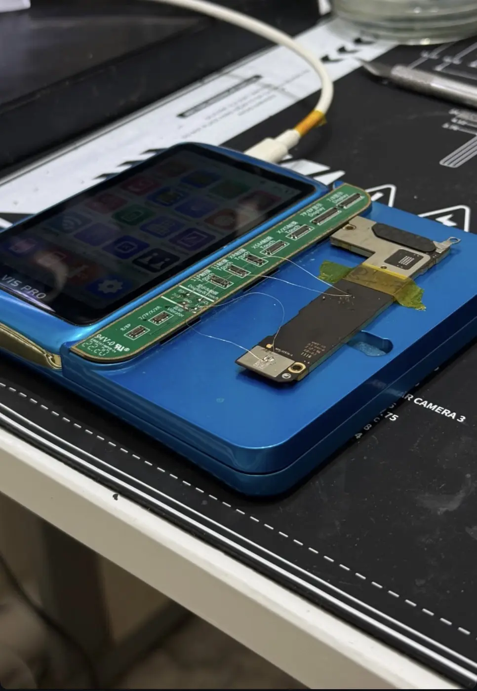 Placa lógica de iPhone em equipamento de reparo com jumpers