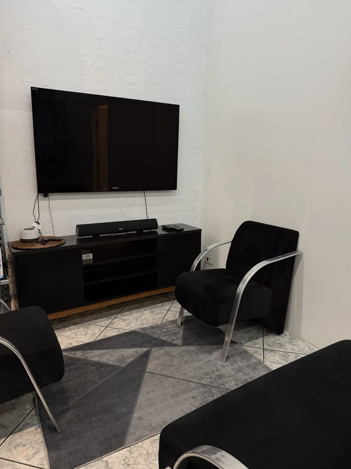 Sala de espera Direct Repair com poltronas e televisão